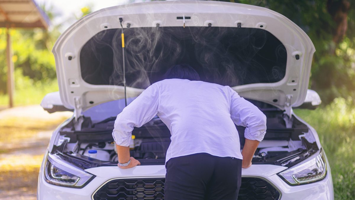 Mann steht vor kaputtem Automotor.