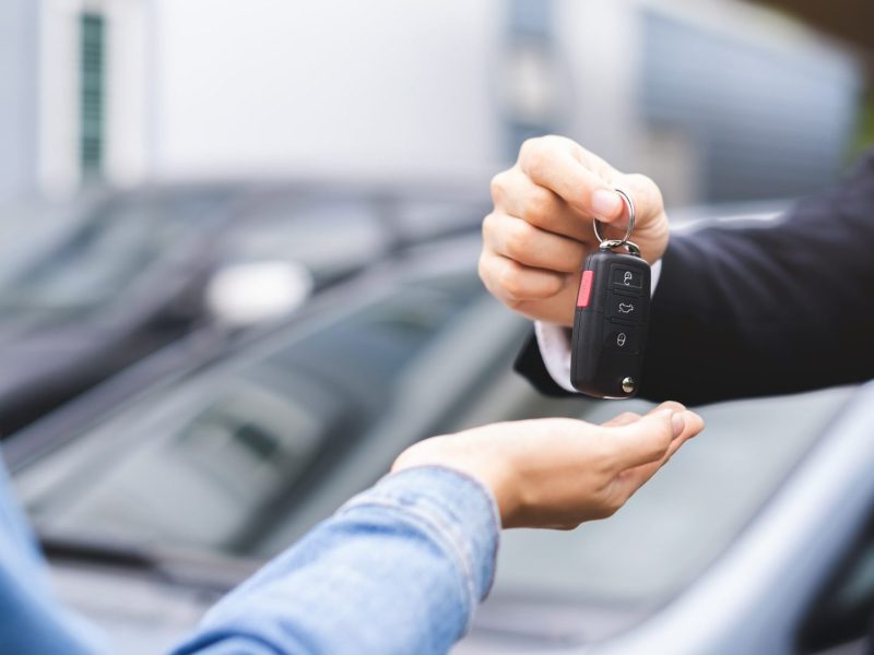 Mann übergibt Autoschlüssel an anderen Mann