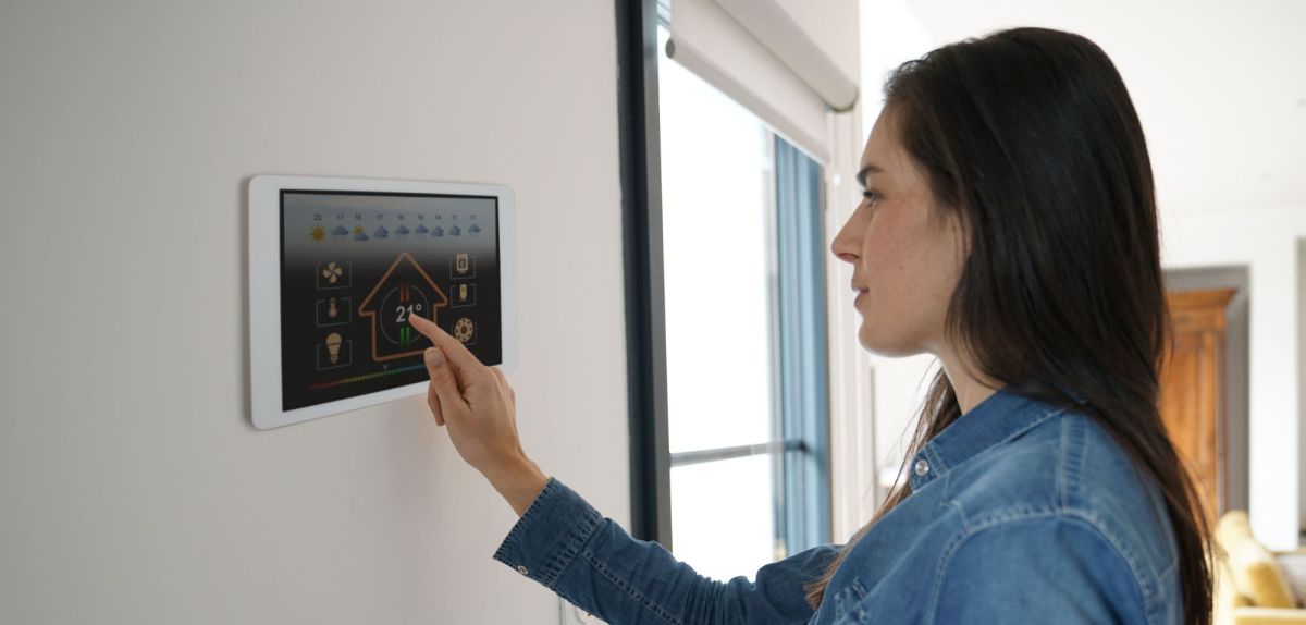 Person bedient eine an der Wand befestigte Steuereinheit für das SmartHome.