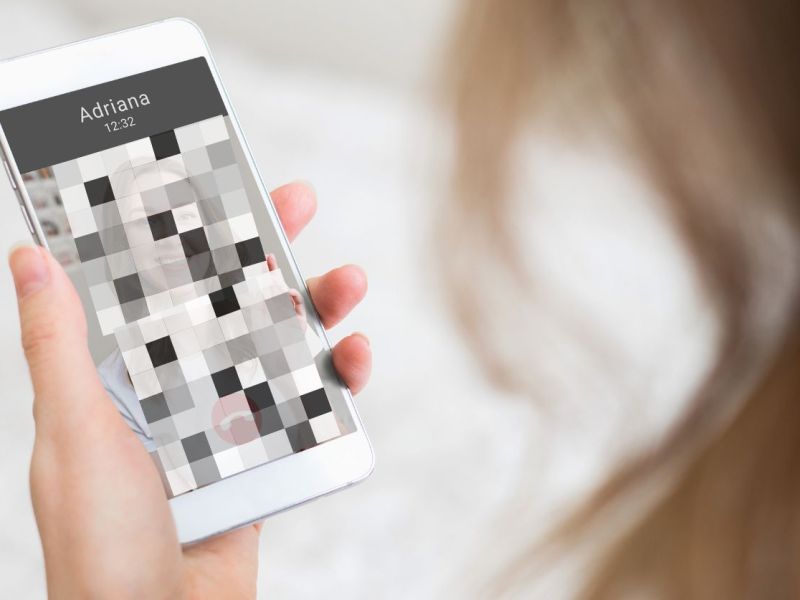 Person schaut auf Handybildschirm mit verpixeltem Bild.