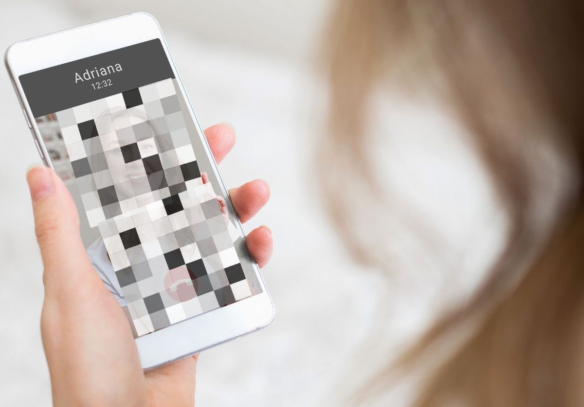 Person schaut auf Handybildschirm mit verpixeltem Bild.
