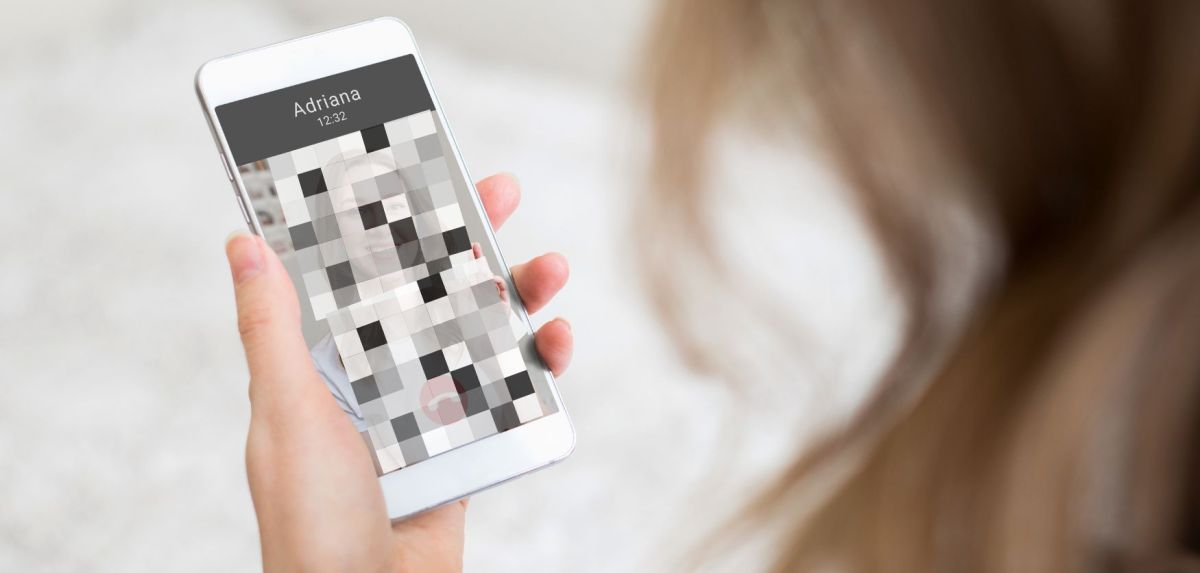 Person schaut auf Handybildschirm mit verpixeltem Bild.