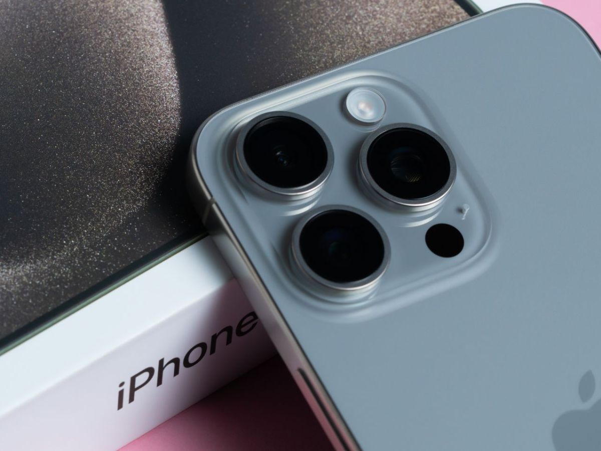 iPhone samt Karton auf pinkem Untergrund.