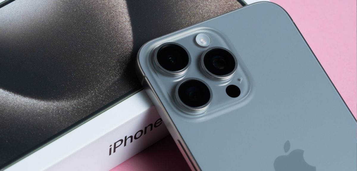 iPhone samt Karton auf pinkem Untergrund.