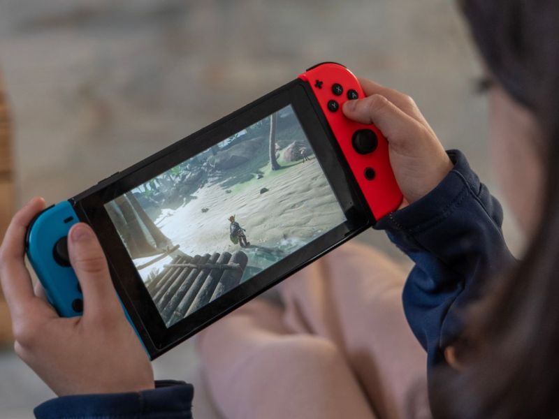Person hält Nintendo Switch Konsole in der Hand.