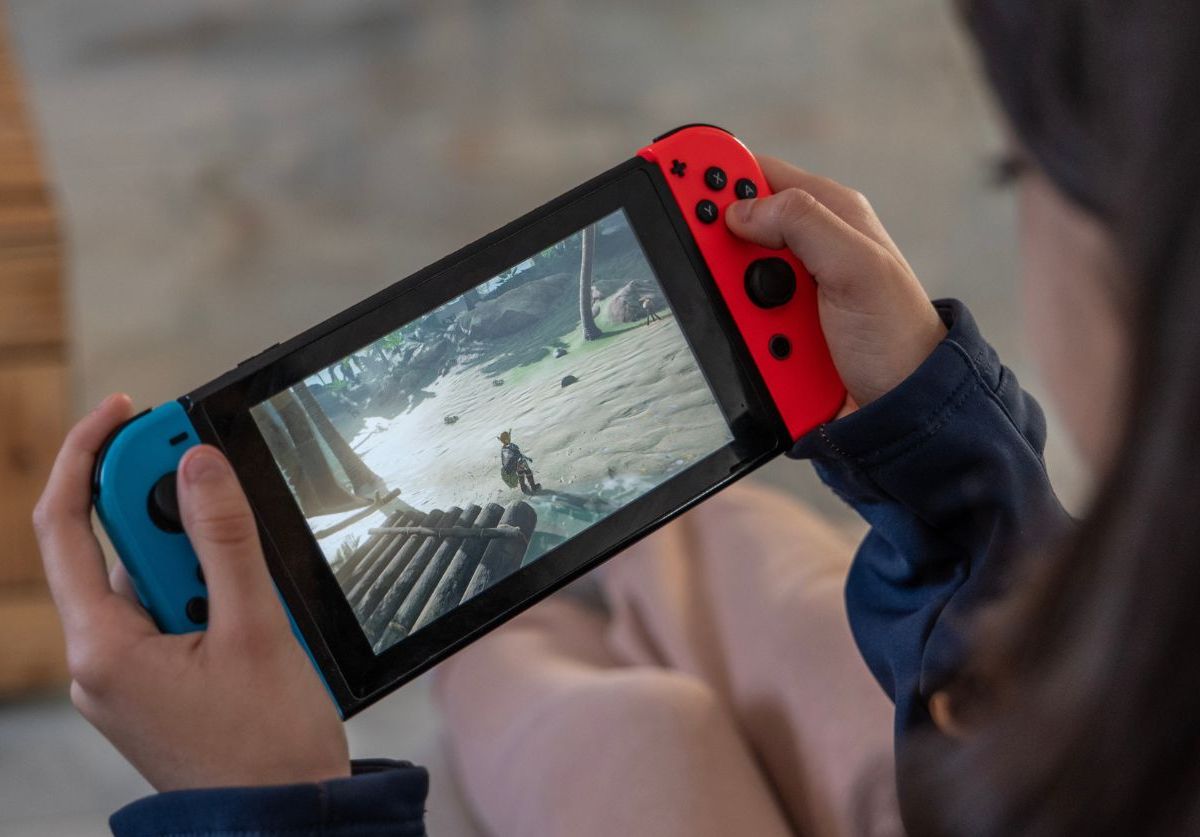 Person hält Nintendo Switch Konsole in der Hand.