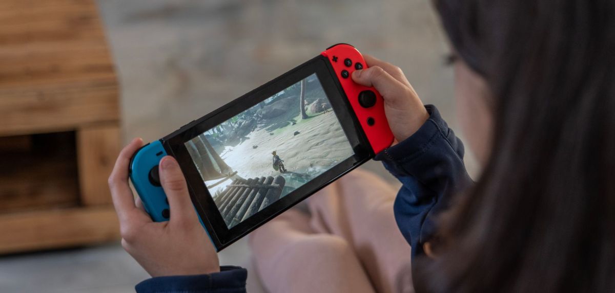 Person hält Nintendo Switch Konsole in der Hand.