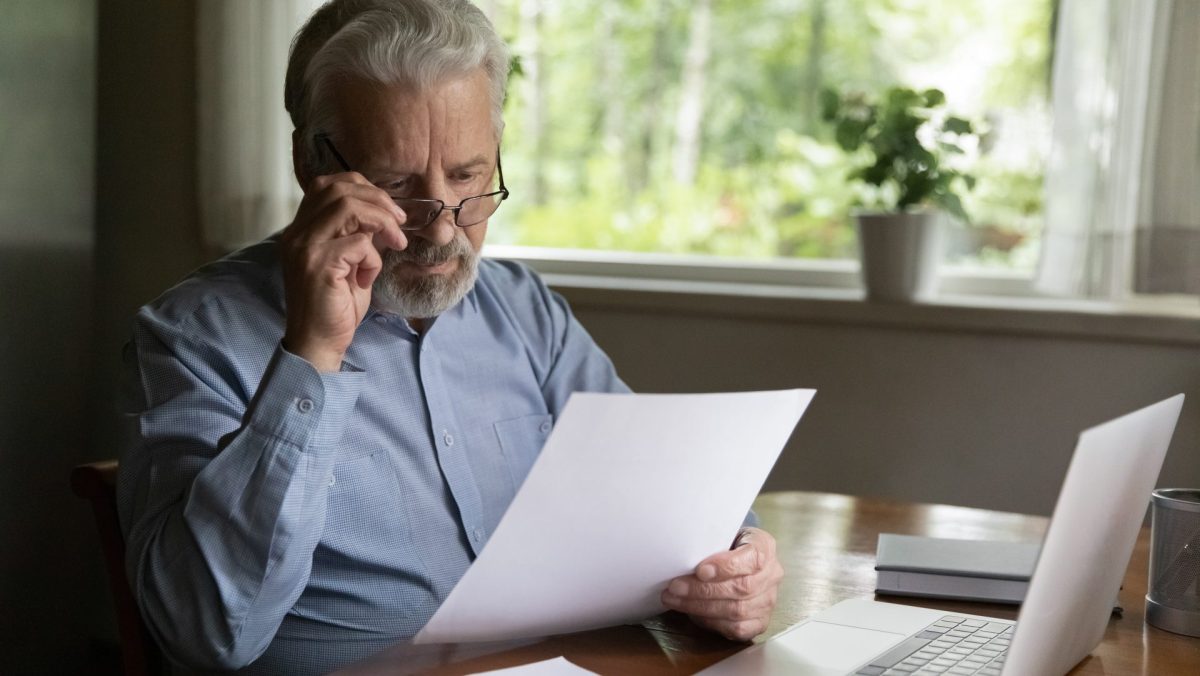 Rentner sitzt am Rechner und liest einen Brief