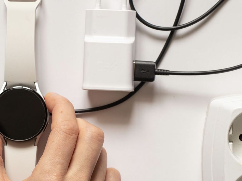 Samsung Galaxy Watch neben einem Ladegerät und einer Mehrfachsteckdose.