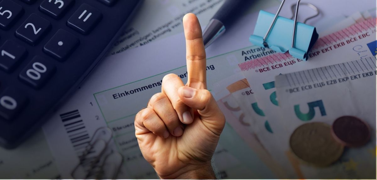 Erhobener Zeigefinger vor einer Einkommensteuererklärung