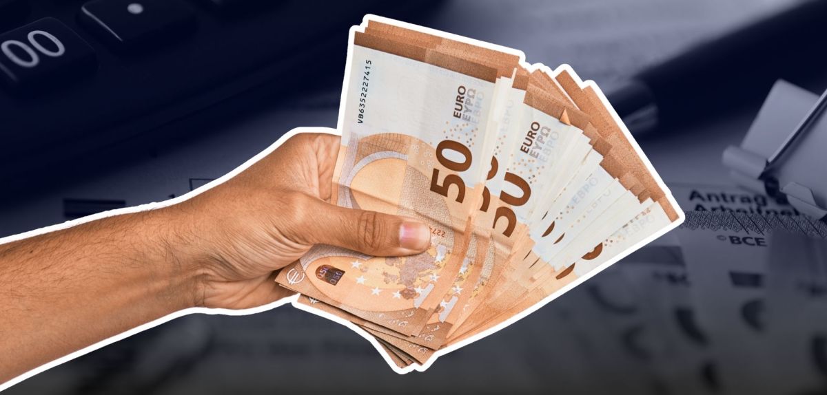 Hand mit mehreren 50-Euro-Scheinen vor einer Steuererklärung