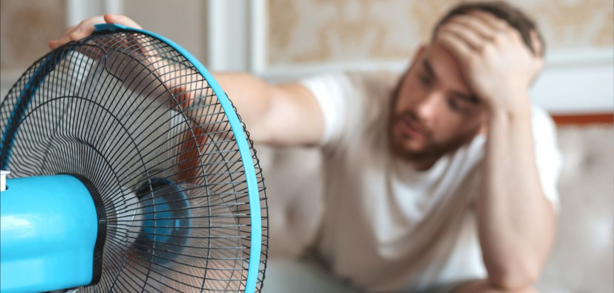 Mann sitzt vor einem Ventilator.