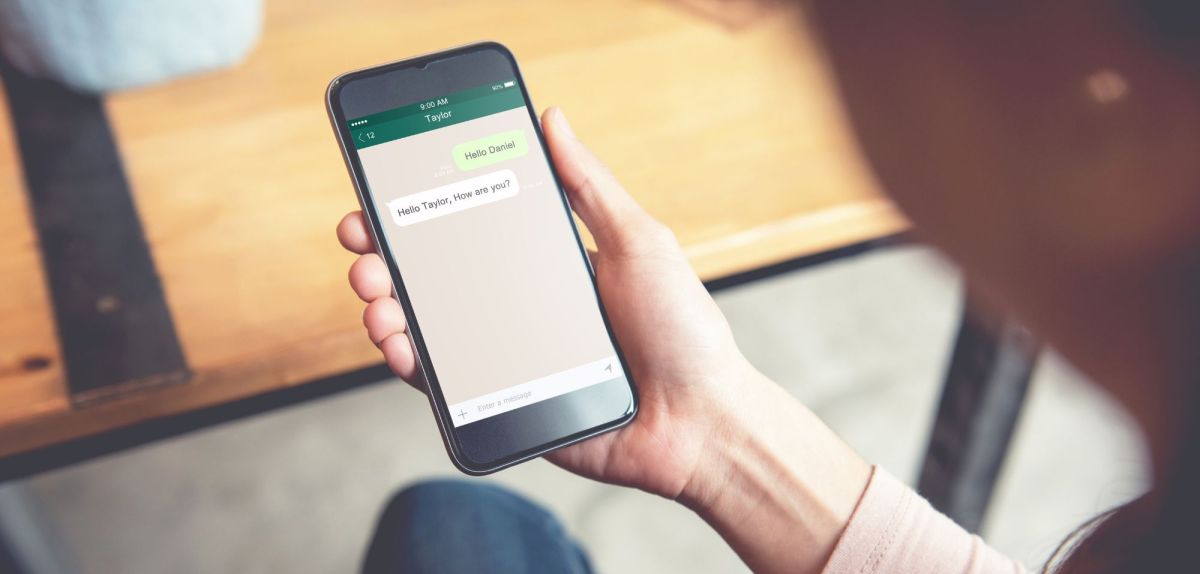 Frau hält ein Handy in der Hand, das ein WhatsApp-Update durchführt.