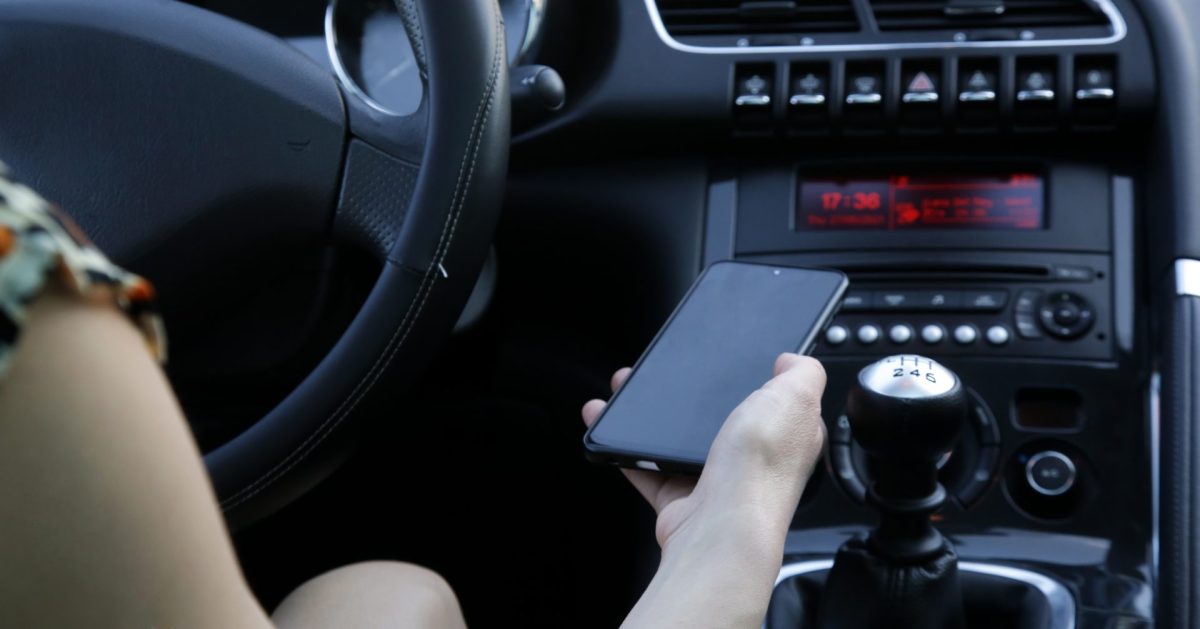 Frau hält Handy im Auto hoch