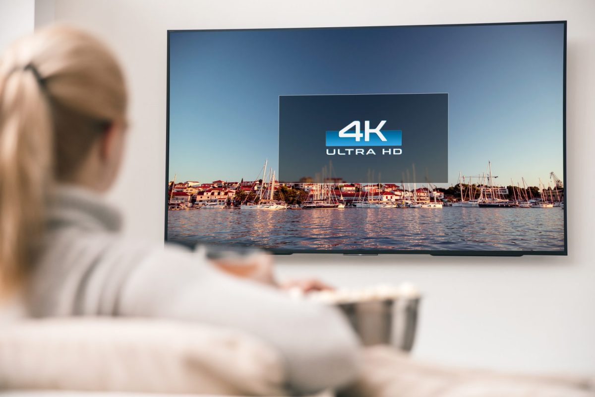 Frau sitzt vor Fernseher an einer Wand